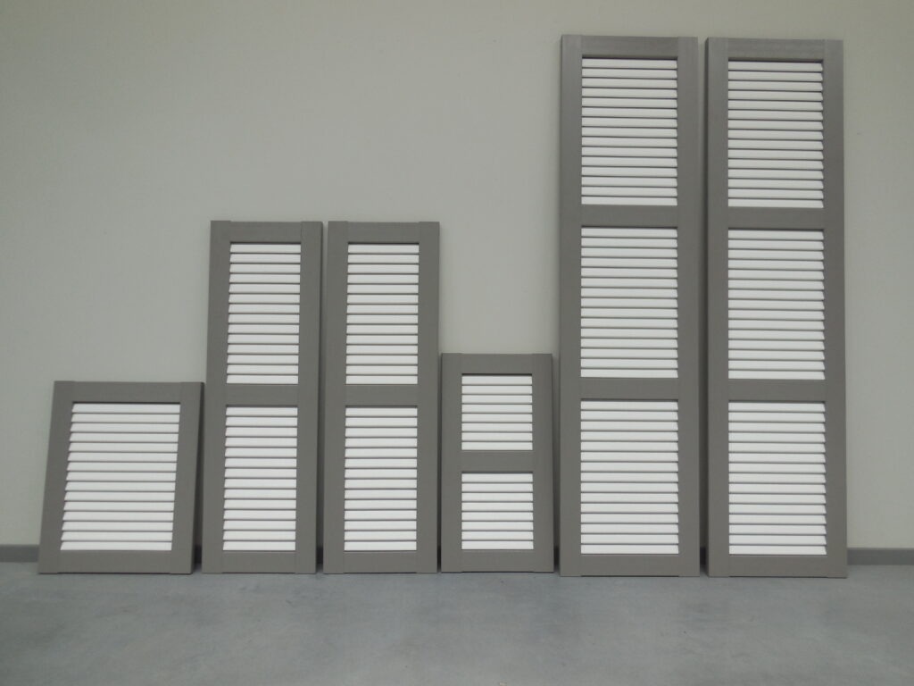 Meerdere PVC raamluiken model 1 open louvre in grijs en wit, met verschillende afmetingen en één of twee tussenliggers – kleurcombinatie mogelijk zonder meerprijs bij Ventinella.