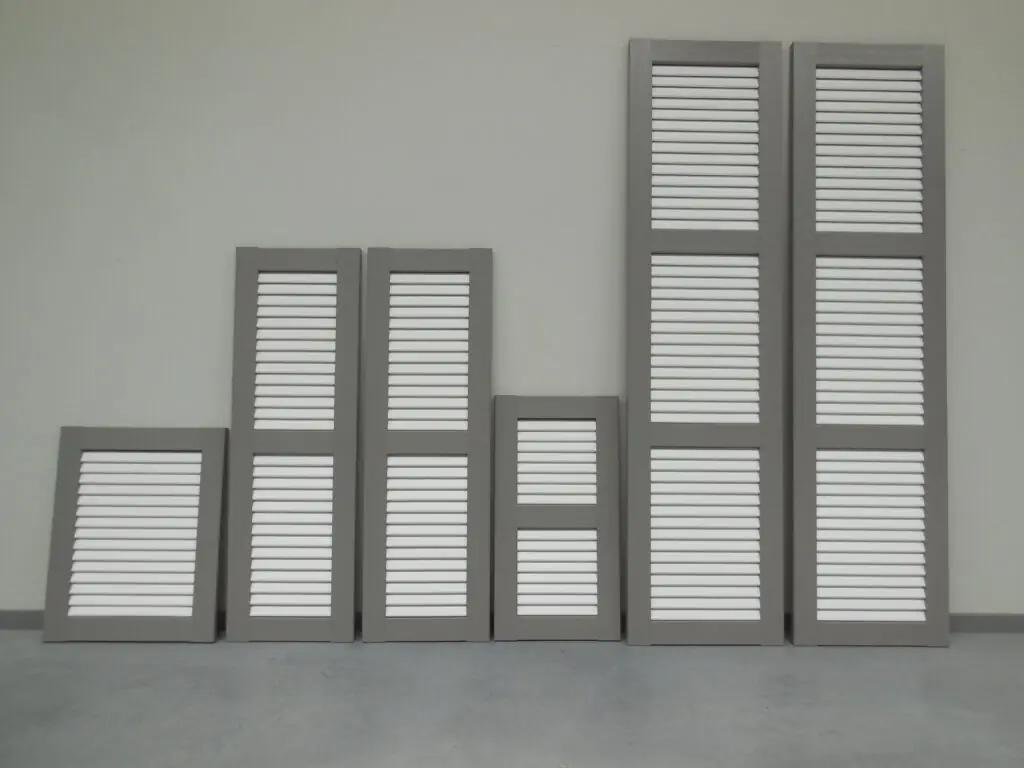 Meerdere PVC raamluiken model 1 open louvre in grijs en wit, met verschillende afmetingen en één of twee tussenliggers – kleurcombinatie mogelijk zonder meerprijs bij Ventinella.