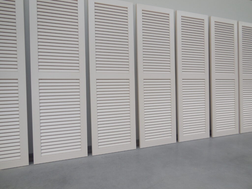 Witte PVC raamluiken model 1 open louvre met één tussenligger, op een rij geplaatst – extra stevigheid bij grotere luiken.