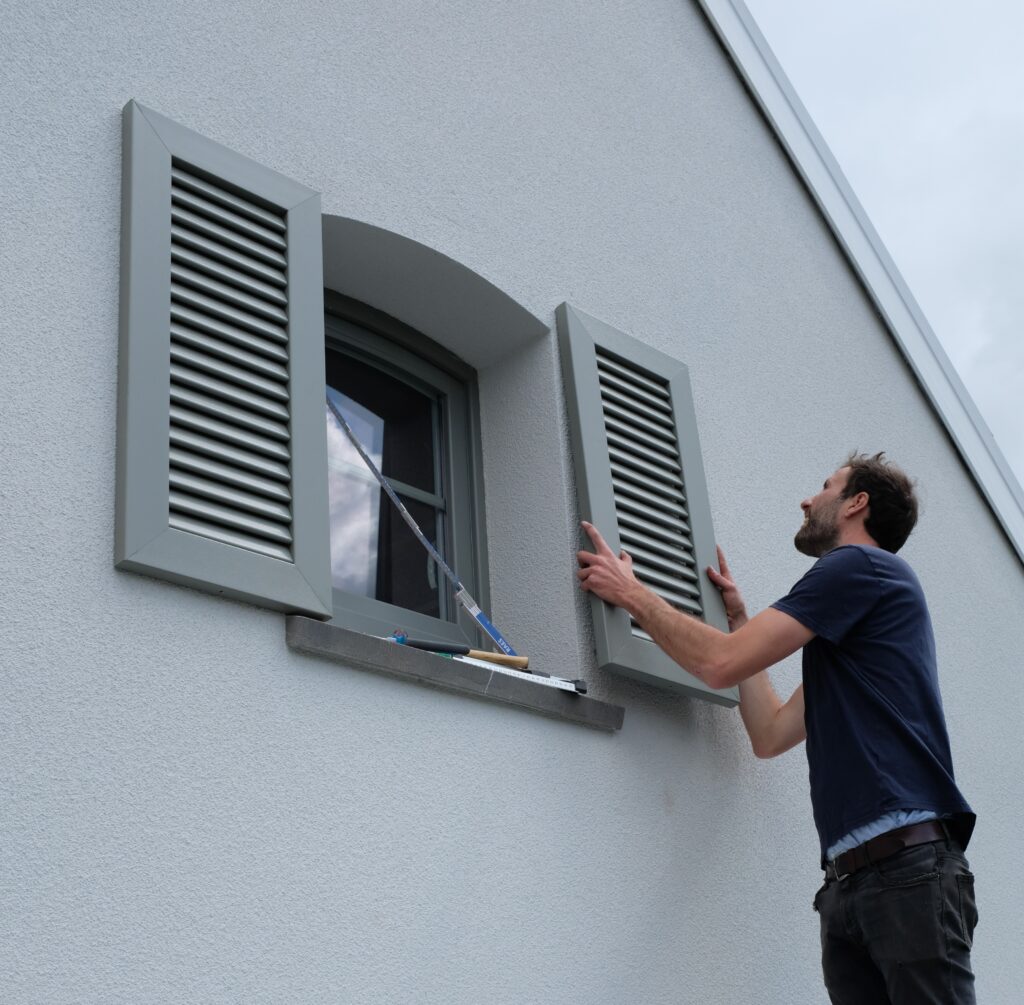 Installateur van Ventinella plaatst een decoratief PVC raamluik – professionele montage en plaatsingsservice voor raamluiken.