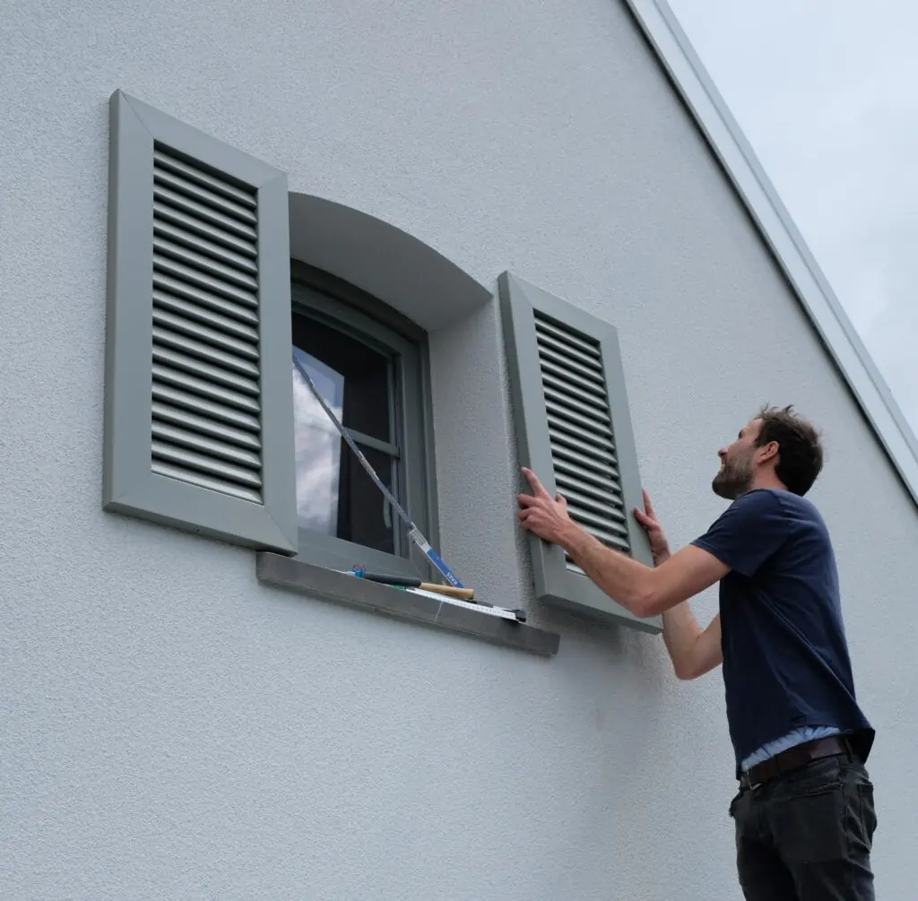 Installateur van Ventinella plaatst een decoratief PVC raamluik – professionele montage en plaatsingsservice voor raamluiken.