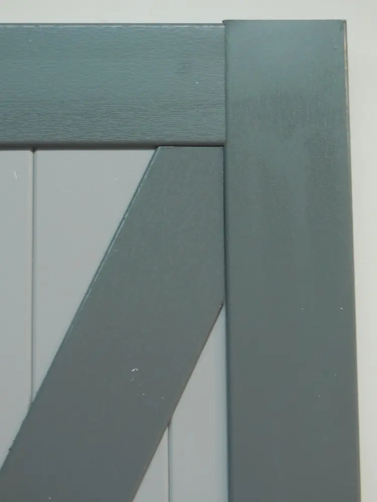 Detail van de hoek van een PVC Z-luik met horizontale planchetten en opgekleefde diagonale sierlijst in grijs en wit – productdetail Ventinella